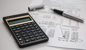 Calcolatrice e foglio con conti della contabilità finanziaria ed economico patrimoniale per enti pubblici.